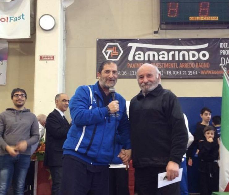 Maestro Carlo Olmo consegna donazione 10000 euro con ambulanza Croce Blu sullo sfondo durante evento arti marziali